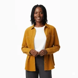 Smiling woman wearing a mustard-colored shirt over a white top.